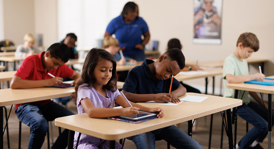 Fotografía de estudiantes completando hojas de trabajo en un centro Kumon.